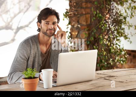 Inizio sempre la mia mattina recuperare in linea. Ritratto di un bel giovane uomo che usa il suo portatile all'aperto. Foto Stock