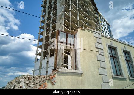 Dettaglio architettonico di alta cornice di costruzione monolitica in cemento in costruzione e vecchia casa demolita di fronte. Sviluppo immobiliare. Foto Stock