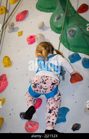 Giovane ragazza che si arrampica e bouldering su un muro Foto Stock