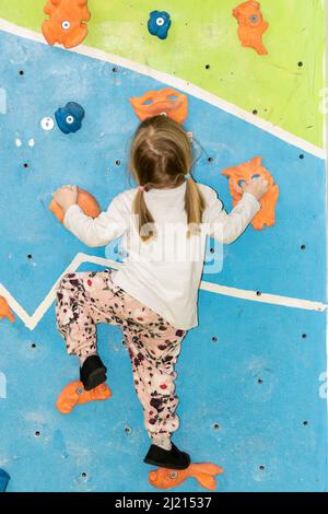 Giovane ragazza che si arrampica e bouldering su un muro Foto Stock