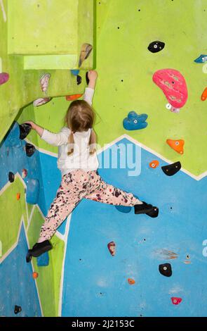 Giovane ragazza che si arrampica e bouldering su un muro Foto Stock