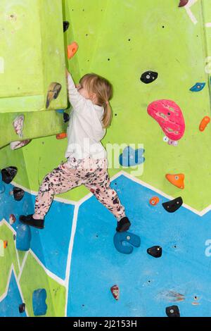 Giovane ragazza che si arrampica e bouldering su un muro Foto Stock