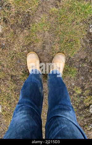 Guardando verso il basso su un paio di jeans e stivali gialli per impieghi  pesanti o scarpe da trekking Foto stock - Alamy