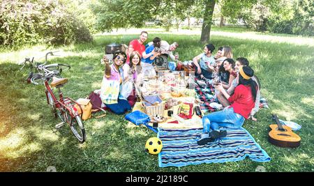 Gruppo di amici felici divertirsi all'aperto con un picnic barbecue con spuntini cibo che beve vino rosso - i giovani che si godono la primavera insieme a barbe Foto Stock