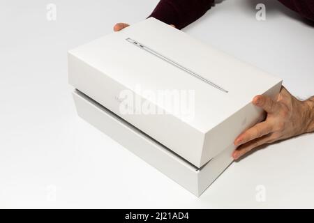 Saratov, Russia - 26 febbraio 2022: Mostra l'apertura della confezione con il nuovo MacBook Air moderno da 13 pollici con vista dall'alto del processore M1, sfondo bianco Foto Stock