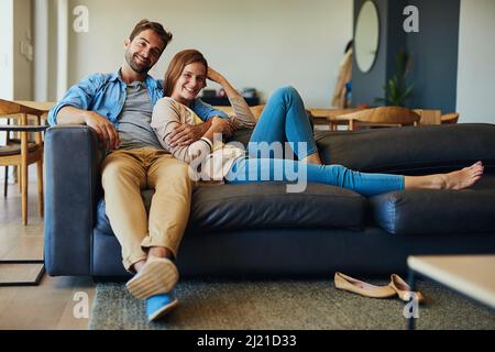 Chilling fuori con il mio numero uno. Ritratto completo di una giovane coppia affettuosa che si rilassa sul divano di casa. Foto Stock