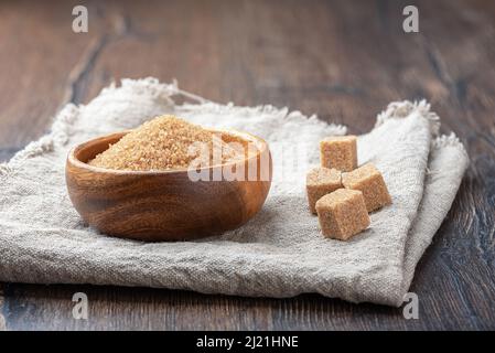 Ciotola di legno con zucchero di canna su tela di tela grossolana. Spazio di copia. Foto Stock