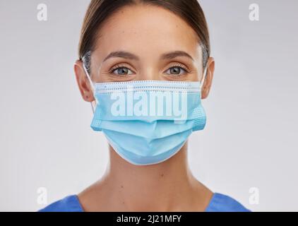 Im qui per aiutare. Scatto di una giovane infermiera femminile sullo sfondo di uno studio. Foto Stock