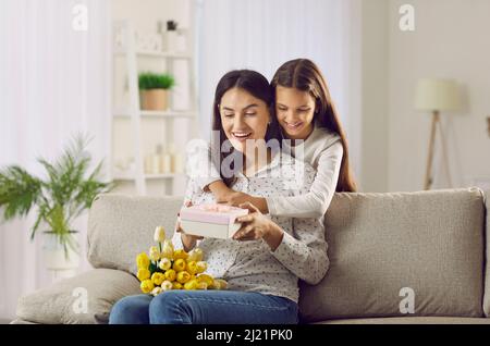 Donna felice riceve bouquet di fiori e presente dal suo bambino in Festa della mamma Foto Stock