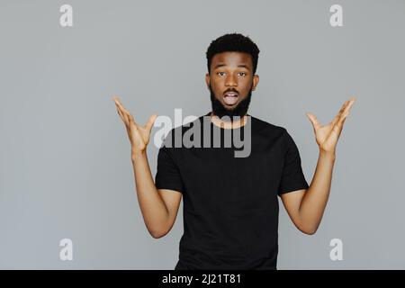 Colpo di testa di goofy sorpreso bug-eyed giovane uomo scuro-skinned studente indossare casual grigio t-shirt fissando la macchina fotografica con il look scioccato, esprimendo gli astoni Foto Stock