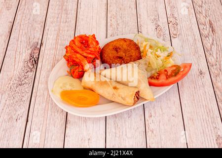 Vassoio di antipasti tipici di cibo indiano in Europa, cipolla bhaji, rotolo di formaggio, samosas, falafel e verdure in salamoia Foto Stock