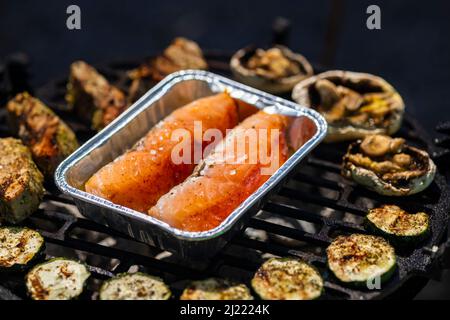 carne di vitello, salmone e zucchine su griglia da giardino con carbone Foto Stock