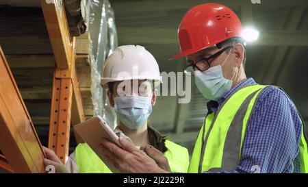 Gli ingegneri maschi e femmine indossano caschi di sicurezza nel magazzino Foto Stock