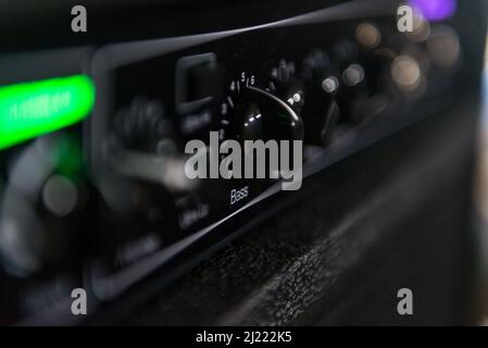 Primo piano della manopola che controlla il suono dei bassi di un amplificatore musicale. Parte di esso appare fuori fuoco Foto Stock