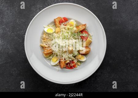 Insalata Caesar con gamberi, su sfondo scuro. Foto Stock