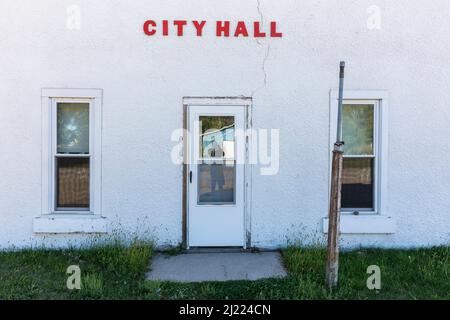 Edificio del municipio abbandonato, cartello, porta e finestre, riflesso di un fotografo nel vetro. Foto Stock