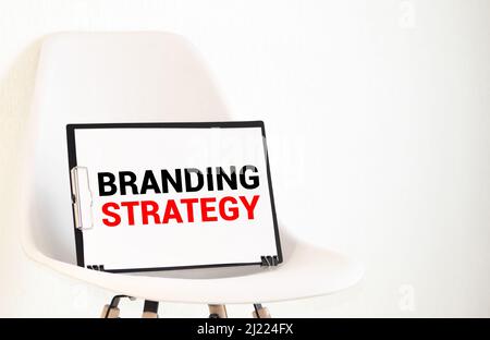 La scrittura di un testo che illustra la strategia di marca. Il concetto di business per l'idea di Marketing Plan scritto su una nota adesiva carta, legno marcatore di sfondo giallo piegato pap Foto Stock