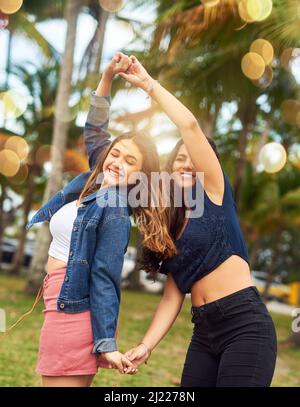 Mi divergo così tanto con lei. Un'inquadratura di due migliori amici femminili giocosi in un parco pubblico. Foto Stock