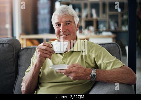 Il tè del pomeriggio va sempre giù bene. Ritratto di un uomo anziano che si gode una bevanda mentre si rilassa sul divano a casa. Foto Stock