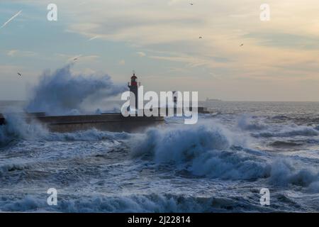 Faro di Foz durante una tempesta al tramonto nell'oceano Atlantico, Porto, Portogallo. Foto Stock