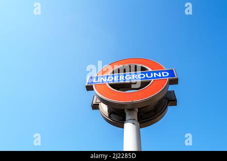 Londra, Regno Unito - 26th marzo 2022: L'iconico cartello rotondale della metropolitana di Londra sullo sfondo di un cielo blu. Foto Stock