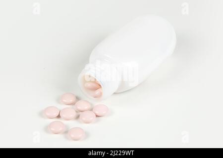 Flacone di farmaco e pillole bianche versate su sfondo bianco. Foto Stock