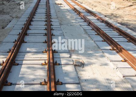 Riparazione dei binari del tram a due vie, posa di rotaie in ferro su traversine in cemento armato, prospettiva di un sito di riparazione all'orizzonte. Foto Stock