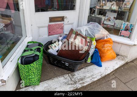 Borse di beni di seconda mano donati lasciate nell'ingresso di un negozio di beneficenza nonostante un avviso che chiede alla gente di non fare questo, Regno Unito Foto Stock