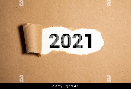 Vision 2021 Goal scritto dietro una carta strappata. Vista dall'alto della carta bianca strappata e del testo 2021 su sfondo rosso. Foto Stock