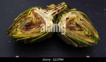 metà dei carciofi fritti cotti su tavola di pietra nera Foto Stock