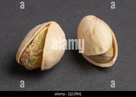 Pistacchi sbucciati e non sbucciati su sfondo scuro. Foto Stock