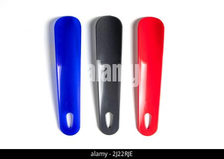 Set di Shoehorns colorati isolati su sfondo bianco. C'è un cucchiaio nero, blu e rosso lungo Foto Stock