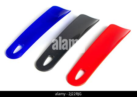 Set di Shoehorns colorati isolati su sfondo bianco. C'è un cucchiaio nero, blu e rosso lungo Foto Stock