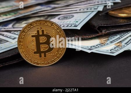 Monete d'oro e centinaia di dollari in portafoglio in pelle. Bitcoin con dollaro in borsa. Profitto dalle valute di cripto minerarie. Minatore con dollari e. Foto Stock