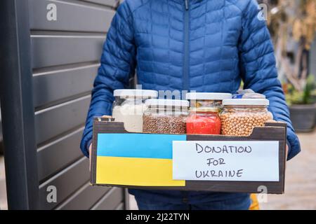 Aiutare il concetto di donazione di volontariato. Una gente che tiene una scatola di donazione piena di cibo nel paese Foto Stock