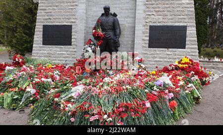 Tallinn, Estonia - 9 maggio 2021: Monumento soldato di bronzo (est: Pronkssõdur). I veterani dell'esercito rosso celebrano la Giornata della Vittoria portando i fiori rossi del garofano Foto Stock