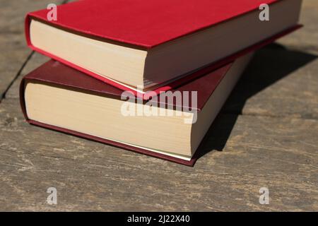 I due libri rossi si trovano uno sopra l'altro su una terrazza di legno in una giornata di sole Foto Stock