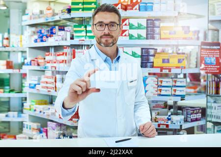 Ive ha ottenuto appena che cosa avete bisogno. Ritratto ritagliato di un bel farmacista maschio maturo che lavora in una farmacia. Foto Stock