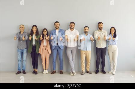 Ritratto di gruppo di uomini e donne d'affari di successo felice dando i pollici in su e sorridendo Foto Stock