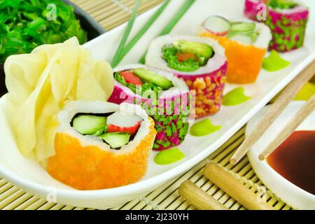 Vari rotoli di sushi Masago Classic Roll e Veggie California Roll con salsa di soia, zenzero, wasabi e insalata di wakame Foto Stock