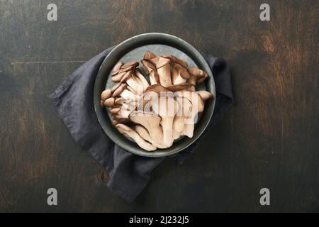 Funghi di ostrica freschi. Stira una vecchia ciotola di deliziosi funghi ostrica biologici su un vecchio sfondo di legno, vista dall'alto con spazio per il testo. Foto Stock