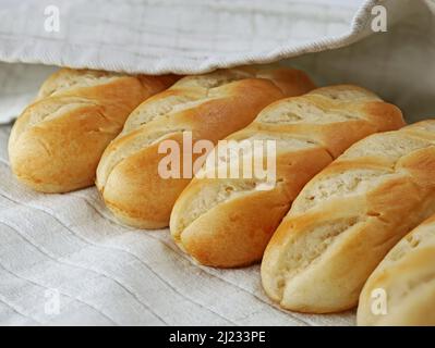 panini al latte francese su asciugamano da cucina grigio, primo piano di deliziosi piatti francesi Foto Stock