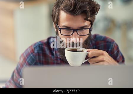 HES la combinazione speciale di artistico, creativo e tecnicamente inclinato. Scatto di un designer che ha un caffè mentre lavora sul suo laptop. Foto Stock