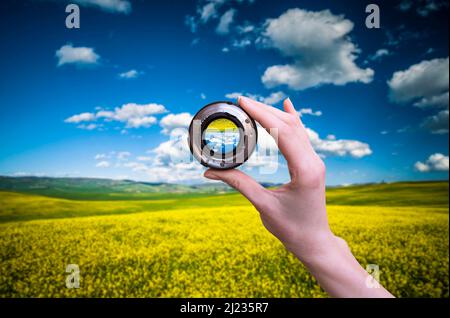 La mano tiene il mirino dell'obiettivo contro la natura in Toscana Foto Stock