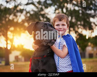 I veri eroi non si levano mai in piedi da soli. Colpo di un ragazzino e il suo cane che indossa i cappi mentre gioca all'esterno. Foto Stock