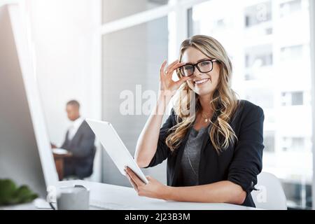Le cose buone accadono a coloro che lavorano duro. Ritratto di una giovane donna d'affari che usa un tablet digitale alla sua scrivania in un ufficio moderno. Foto Stock