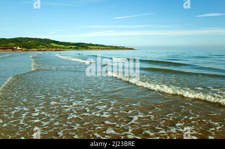 Onde dolci che si rotolano sulla spiaggia di Traayeth ora sulla baia di Dulas vista dal sentiero costiero sull'isola di Anglesey, Galles del Nord Regno Unito, Foto Stock