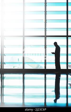Male ti chiami quando atterrò. Scatto di un viaggiatore non identificabile utilizzando il suo smartphone in una sala d'attesa aeroporto. Foto Stock