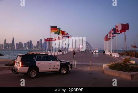 Doha, Qatar. 29th Mar 2022. Le bandiere delle varie nazioni partecipanti sono viste su una piazza accanto al 'World Cup Countdown Clock' per la Coppa del mondo 2022 in Qatar sulla Corniche Promenade con lo skyline della West Bay di Doha. Doha ospiterà il Congresso FIFA il 31 marzo e l'estrazione della Coppa del mondo 2022 in Qatar il 1 aprile. Credit: Christian Charisius/dpa/Alamy Live News Foto Stock