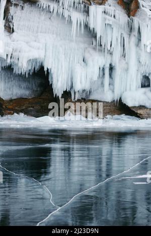 Un colpo verticale di un corpo d'acqua ghiacciato contro una scogliera con grandi ghiacciate Foto Stock